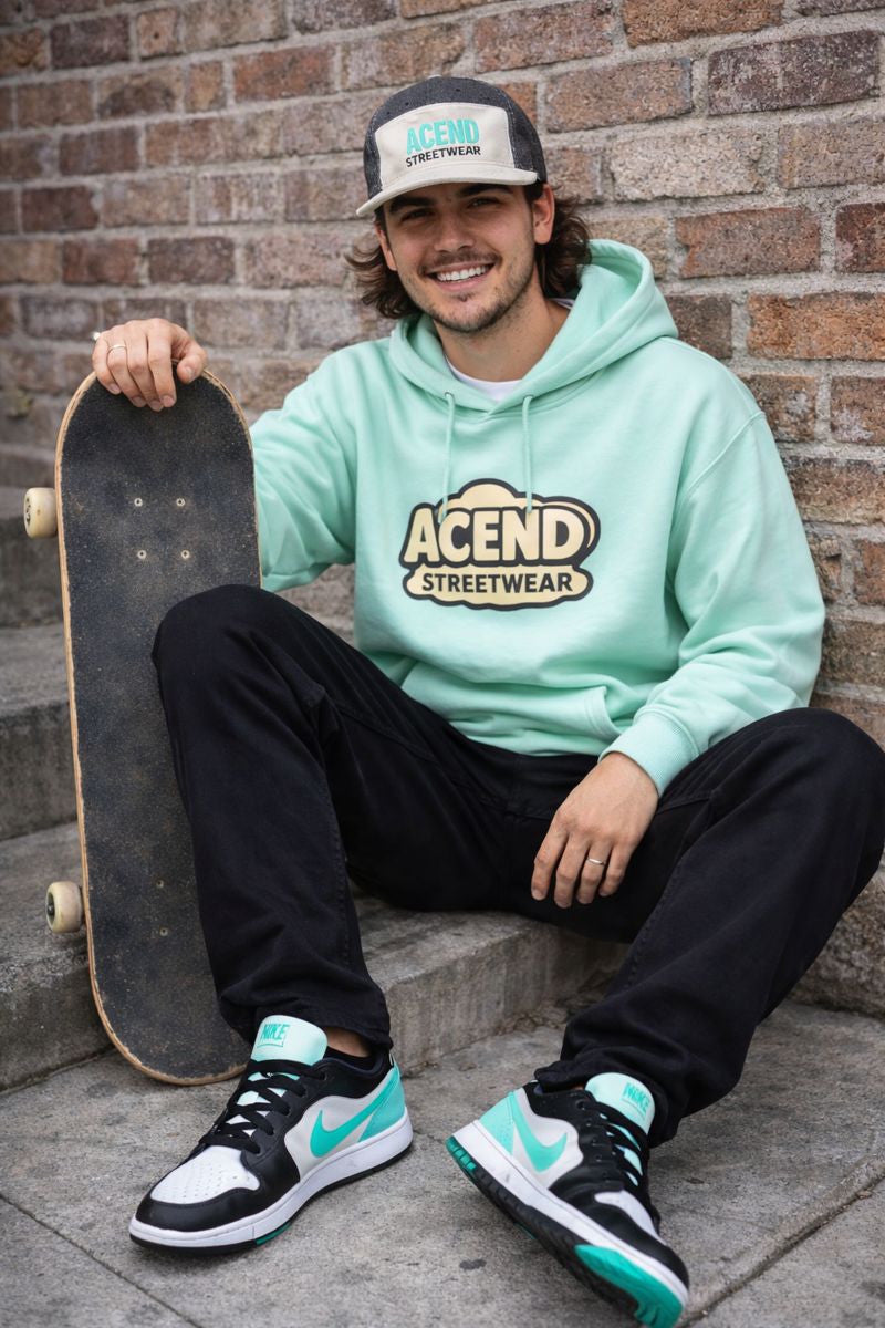 Original archive image of a model with skateboard wearing a mint hoodie, cream and black cap, black pants and mint-accented low-top sneakers
